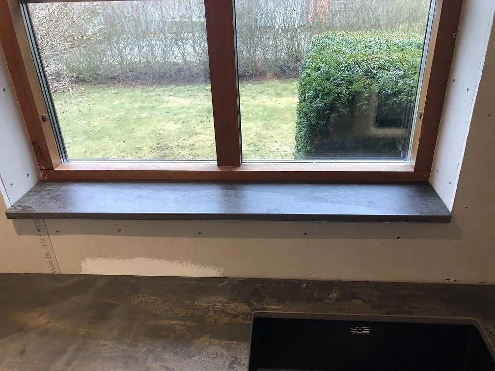 Köksbänkskiva i Dekton Trilium, matt med oxiderad metall-look, monterad i situ längs väggen i ett kök under montering i Jonstorp.