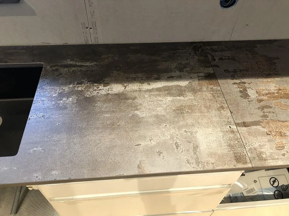 Köksbänkskiva i Dekton Trilium med underlimmad mörk diskho och stänkkant mot vägg, matt charkoalgrå sten, kök i Jonstorp.