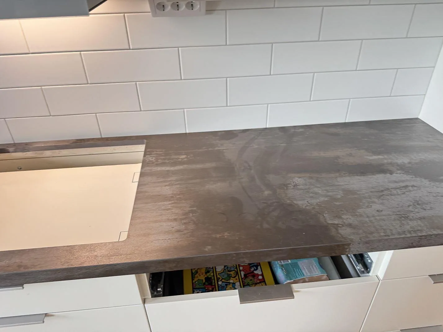 Bred vy av köksbänkskiva i matt Dekton Trilium, 20 mm, längs vit kaklad vägg i ett kök i Malmö.