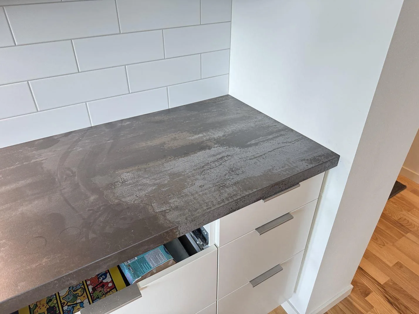Köksbänkskiva i matt Dekton Trilium över vita lådor, med gråbrun keramisk yta i Malmö.