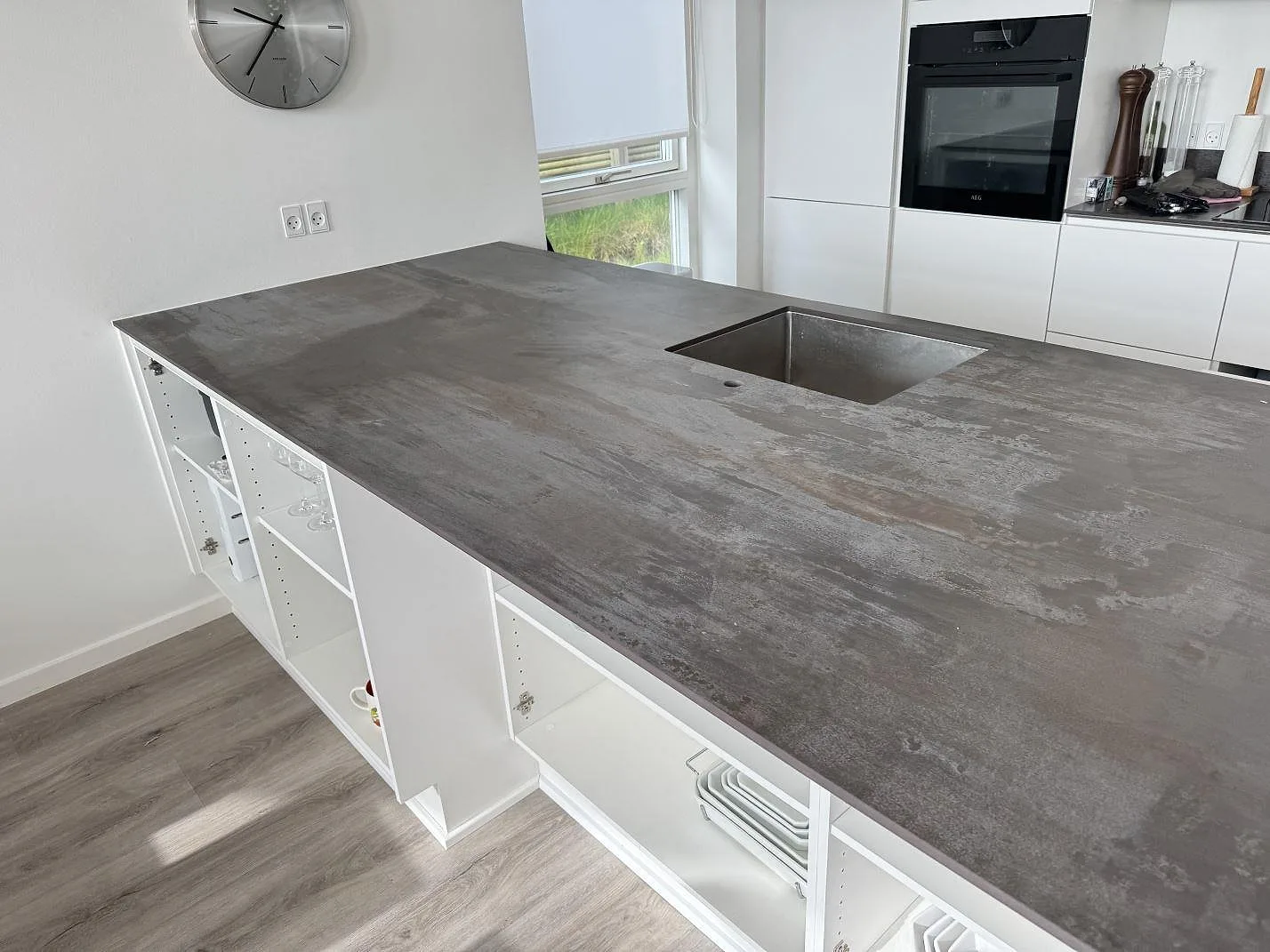 Köksbänkskiva i matt gråbrun Dekton Trilium keramik med diskho och öppna vita skåpsidor i Snekkersten.