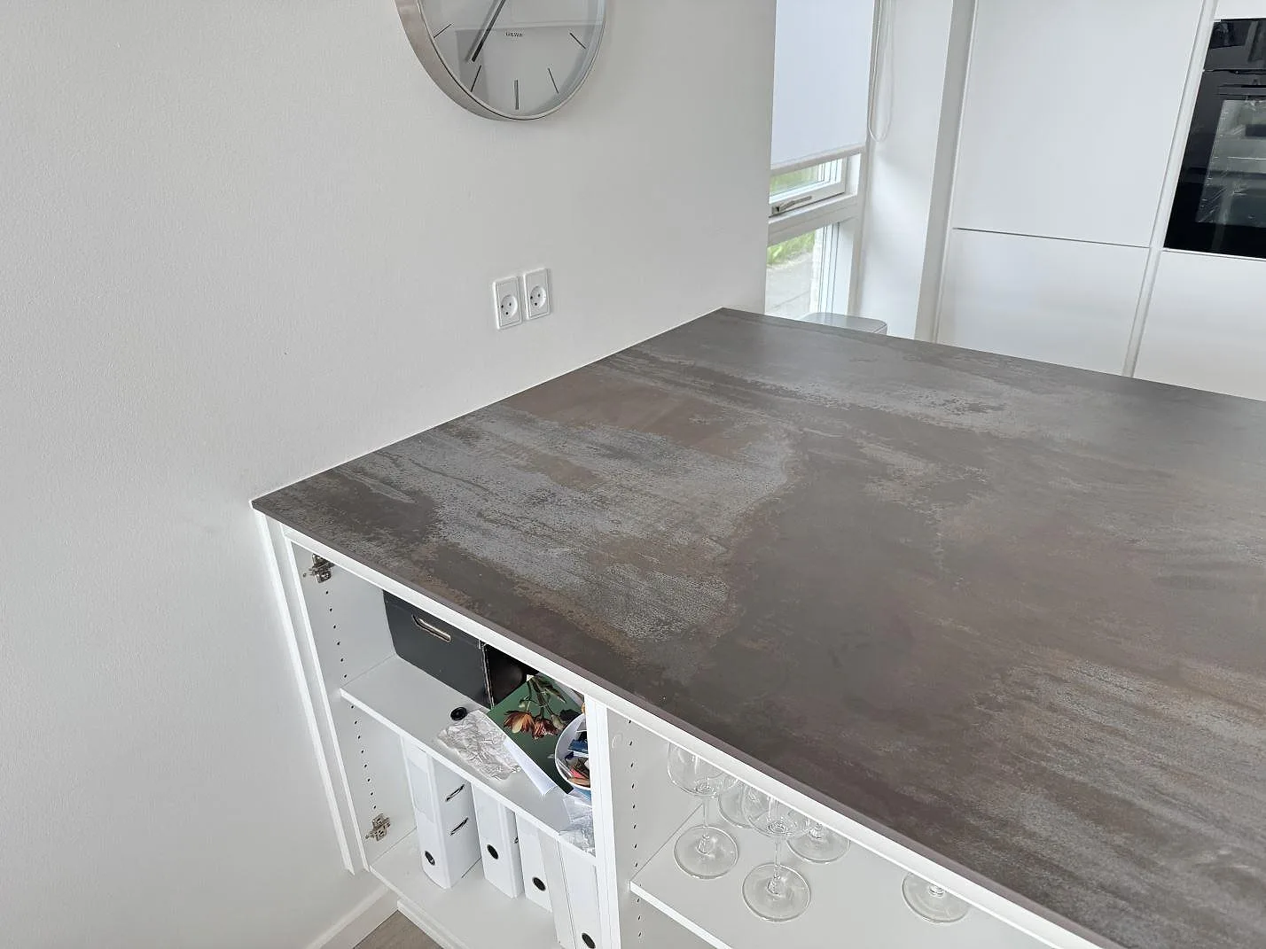 Detalj av matt Dekton Trilium bänkskiva i gråbrun keramik vid vägg och öppna hyllor i kök i Snekkersten.