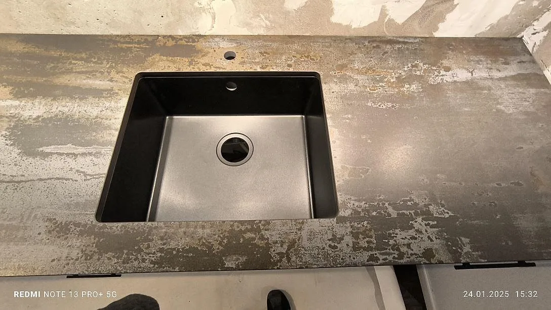 Närbild på matt Dekton Trilium i keramik runt diskhon, med rosttonad yta i kök i Solna.