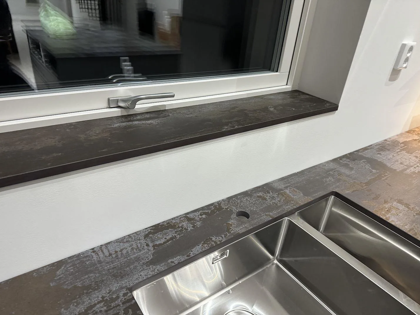 Bänkskiva och fönsterbänk i matt Dekton Trilium vid rostfri diskho i ett kök i Torslanda.