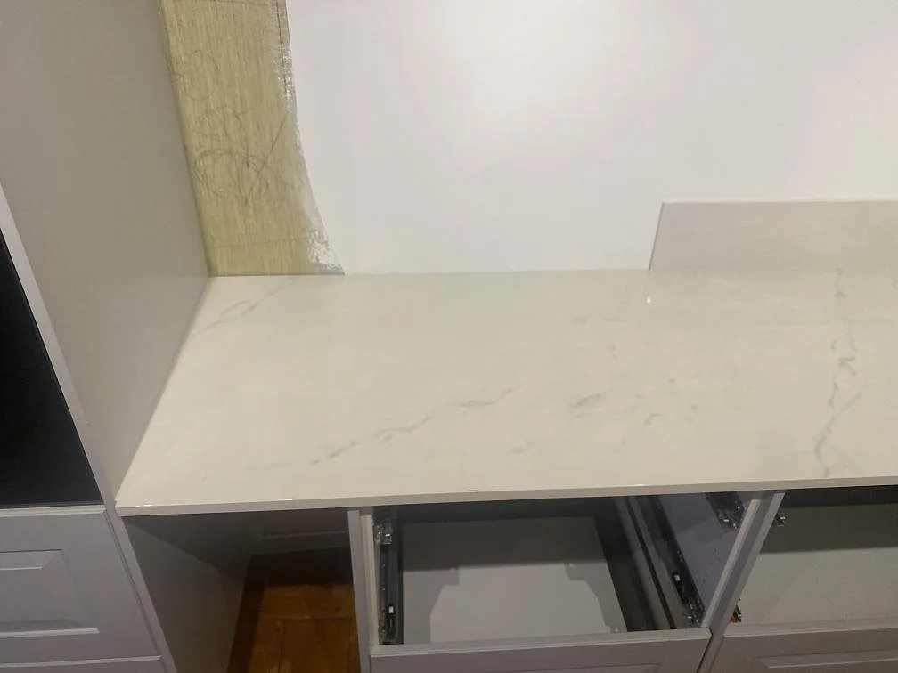 Ljus Dekton Tundra 19 köksbänkskiva i polerad keramik med låg stänkkant och öppna lådsektioner under montering i Åsa.