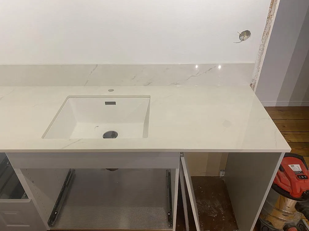 Vit underlimmad diskho i en polerad Dekton Tundra 19 köksbänkskiva med matchande stänkskydd i ett kök i Åsa.