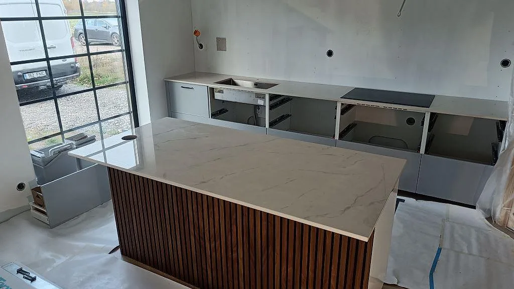 Köksbänkskiva och köksö i polerad Dekton Tundra 19, 20 mm, under montering i ett ljust kök i Asmundtorp.