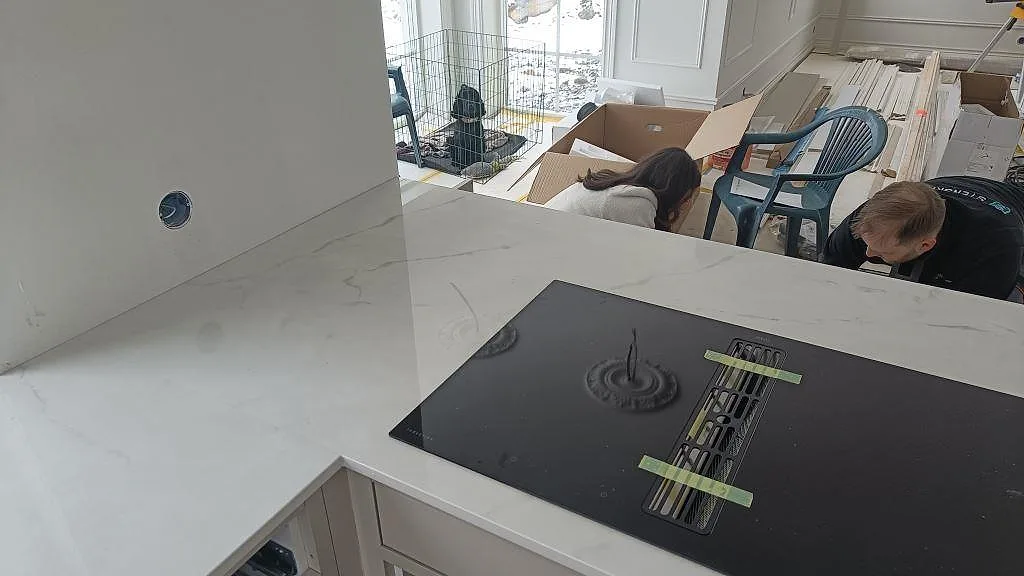 Polerad Dekton Tundra bänkskiva med induktionshäll och spegelblank yta i ett kök under montering i Borås.