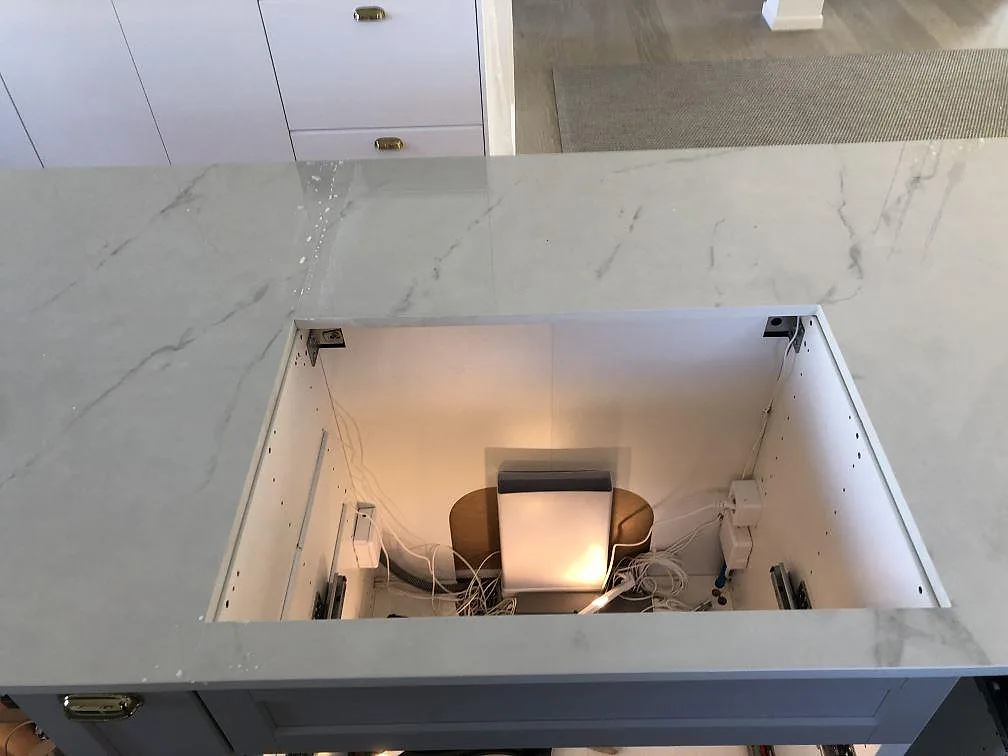 Köksö i polerad Dekton Tundra med urtag i en köksbänkskiva, ljus ådring, under montering i ett kök i Halmstad.