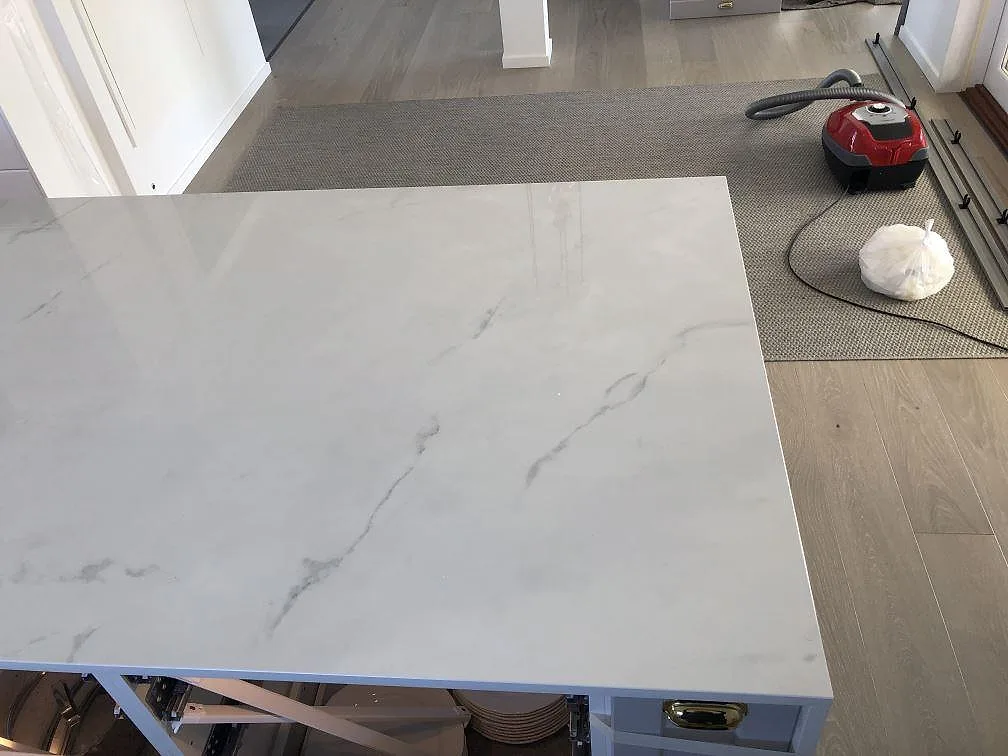 Köksö i Dekton Tundra med polerad yta och mjuk grå ådring, monterad i ett kök i Halmstad.