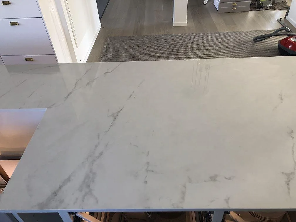 Polerad Dekton Tundra köksbänkskiva med diskret grå ådring sedd i ögonhöjd i ett kök i Halmstad.
