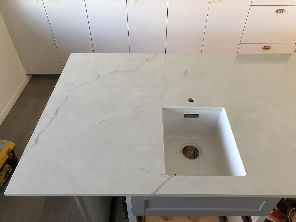 Underlimmad diskho i en köksbänkskiva i Dekton Tundra, polerad ljus yta med grå ådring, i ett kök i Halmstad.