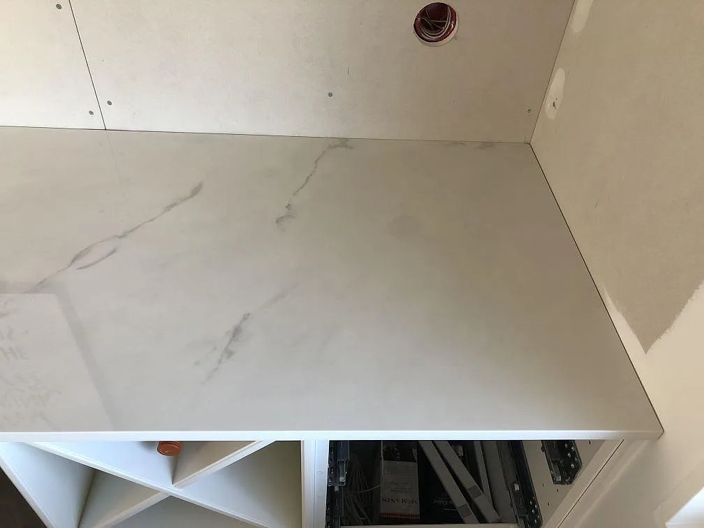 Toppvy av en köksbänkskiva i Dekton Tundra, polerad ljus yta med grå ådring, under montering i ett kök i Halmstad.