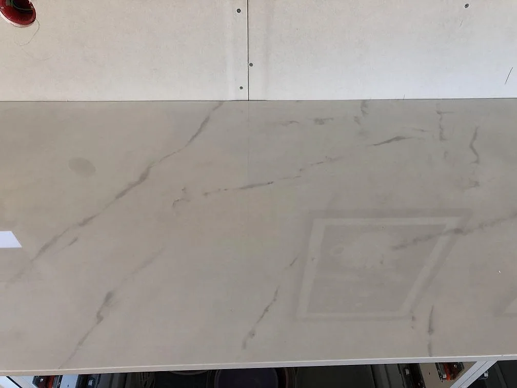 Ljus köksbänkskiva i Dekton Tundra med fin marmorlik ådring mot bar vägg under montering i Halmstad.