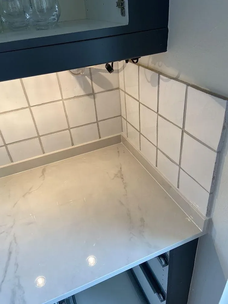 Blank polerad Dekton Tundra 19 med marmorerad yta och matchande stänkskydd vid kaklad köksvägg i Löddeköpinge.