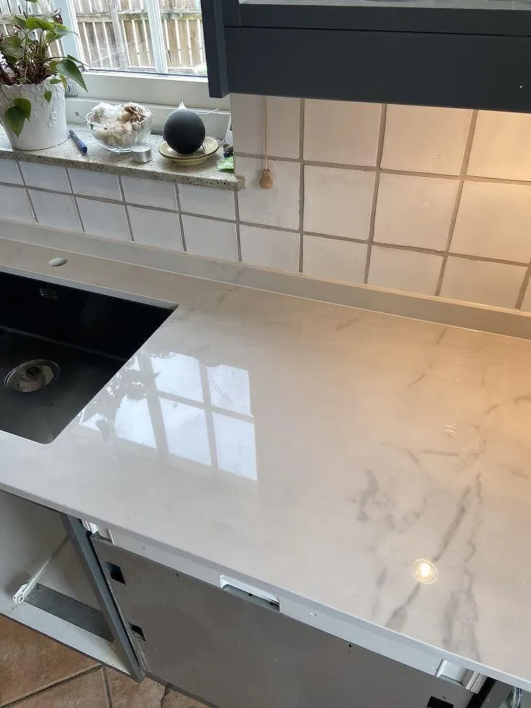 Polerad Dekton Tundra 19 som köksbänkskiva med rostfri diskho, svart häll och blank vit ådring i Löddeköpinge.