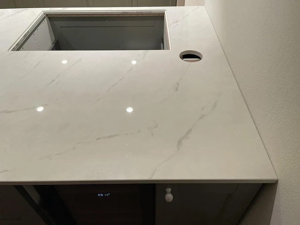 Polerad köksbänkskiva i Dekton Tundra med urtag för planmonterad häll och blandarehål i ett kök i Trelleborg.