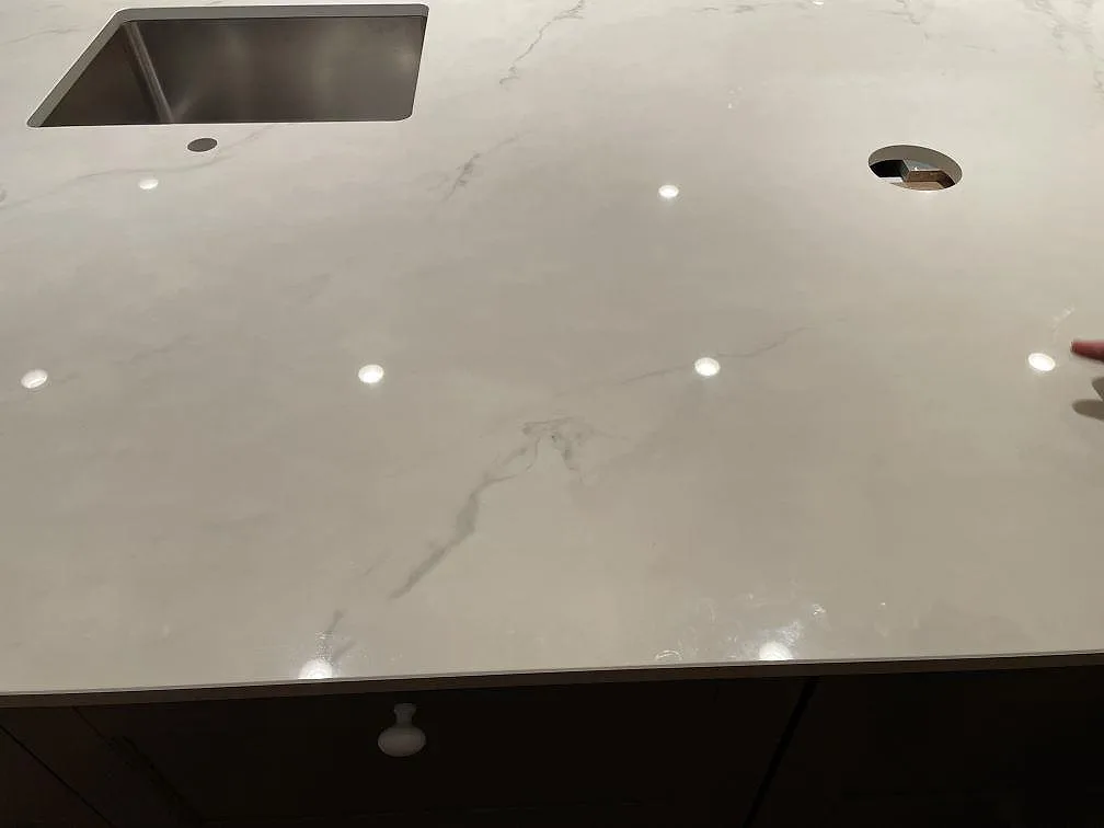 Vit Dekton Tundra köksbänkskiva med grå marmorådring, diskho och hällurtag i ett kök i Trelleborg.