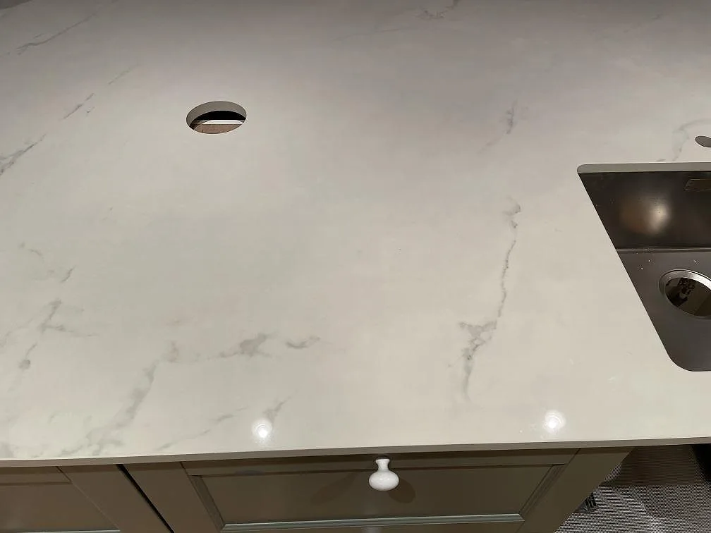 Polerad köksbänkskiva i Dekton Tundra med tydlig grå ådring och blandarehål i ett kök i Trelleborg.
