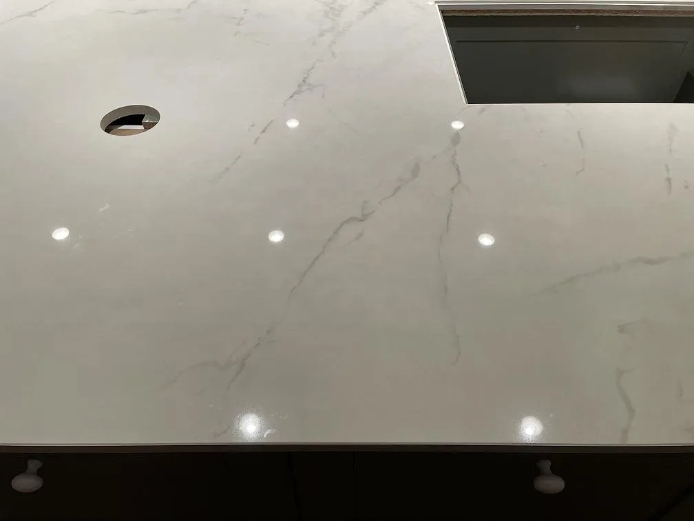 Köksbänkskiva i vit Dekton Tundra med diskbänksö och hällurtag under montering i ett kök i Trelleborg.