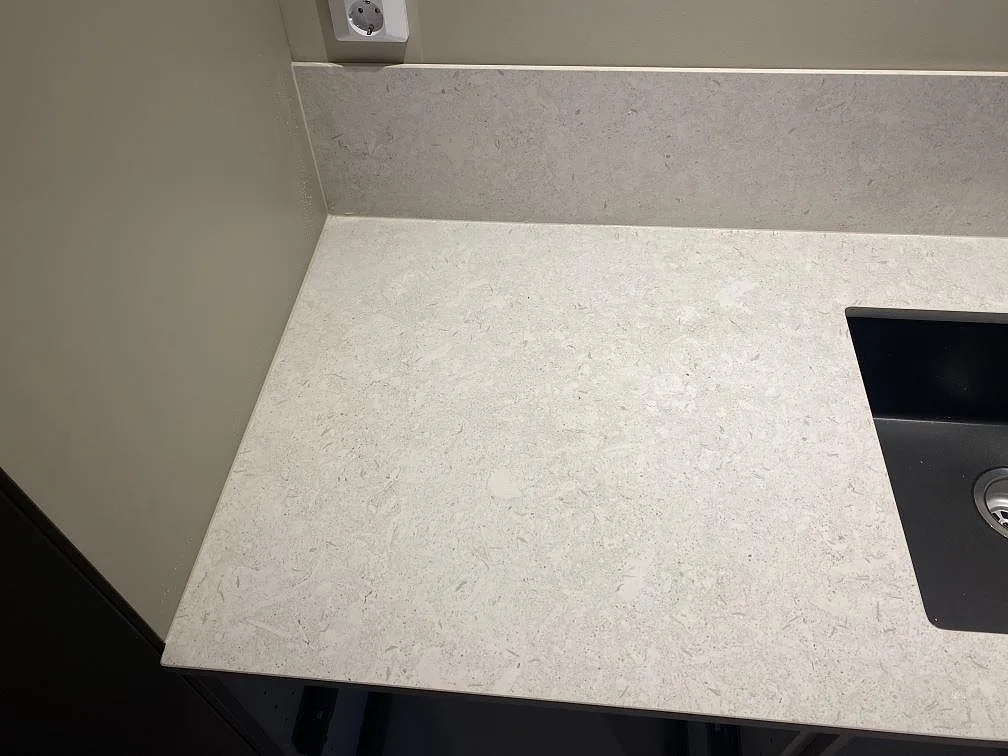 Ytdetalj av matt Dekton VK01 Nebbia på väggbänk med låg stänkkant och ljusgrå ådring i Älmhult.
