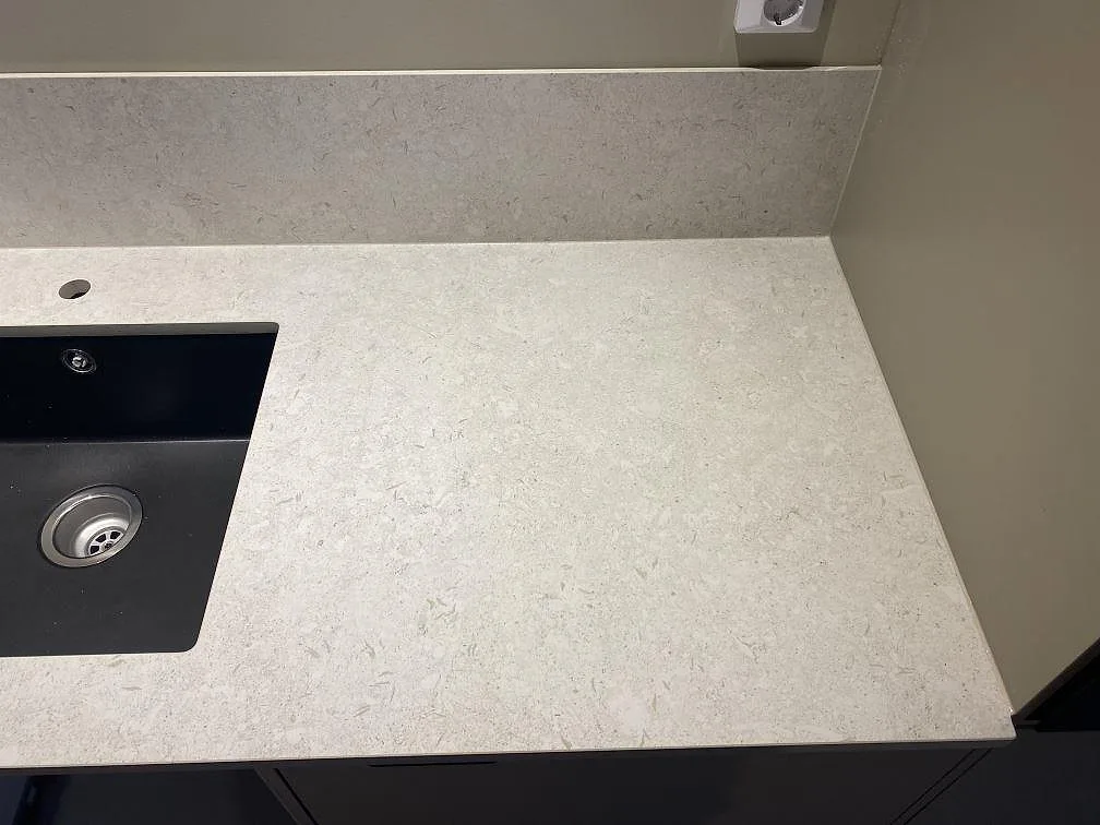 Höger del av köksbänkskivan i matt Dekton VK01 Nebbia med diskho, ljus keramikyta och låg stänkkant i Älmhult.