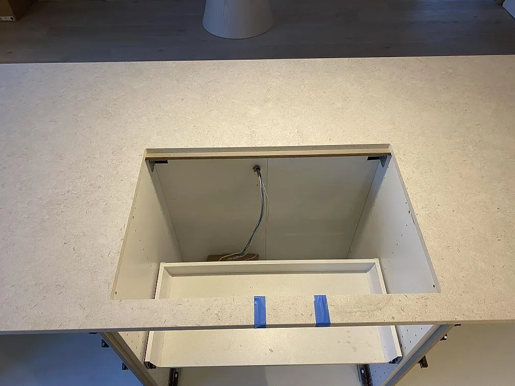 Köksö i matt Dekton VK01 Nebbia med urtag för häll under montering i ett kök i Älmhult.
