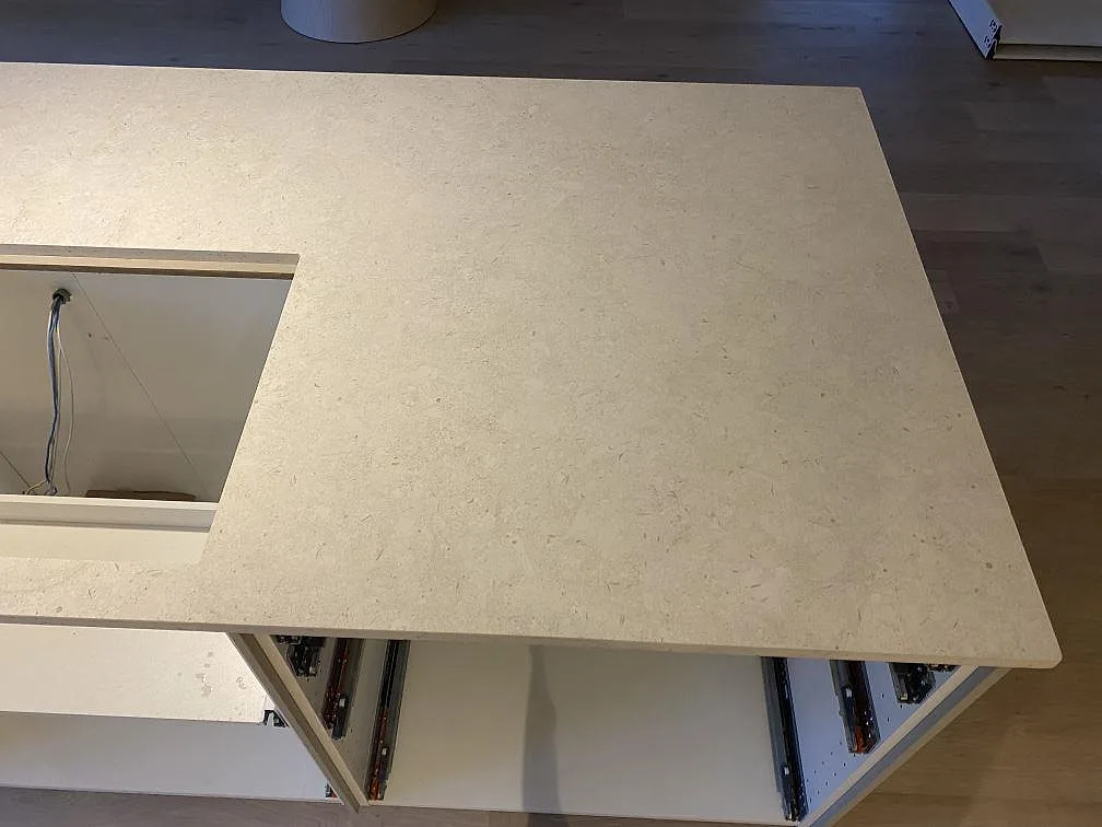 Närbild av köksö i matt Dekton VK01 Nebbia med hällurtag och öppen stomme under montering i Älmhult.
