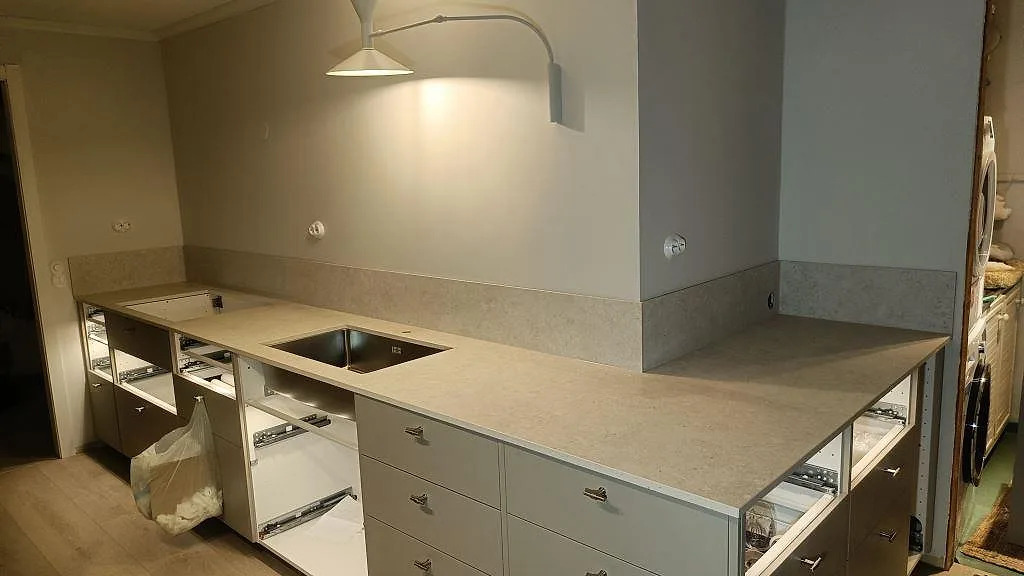 Köksbänkskiva i matt Dekton VK01 Nebbia med L-form, halvö och underlimmad dubbelho i ett kök i Asarum.