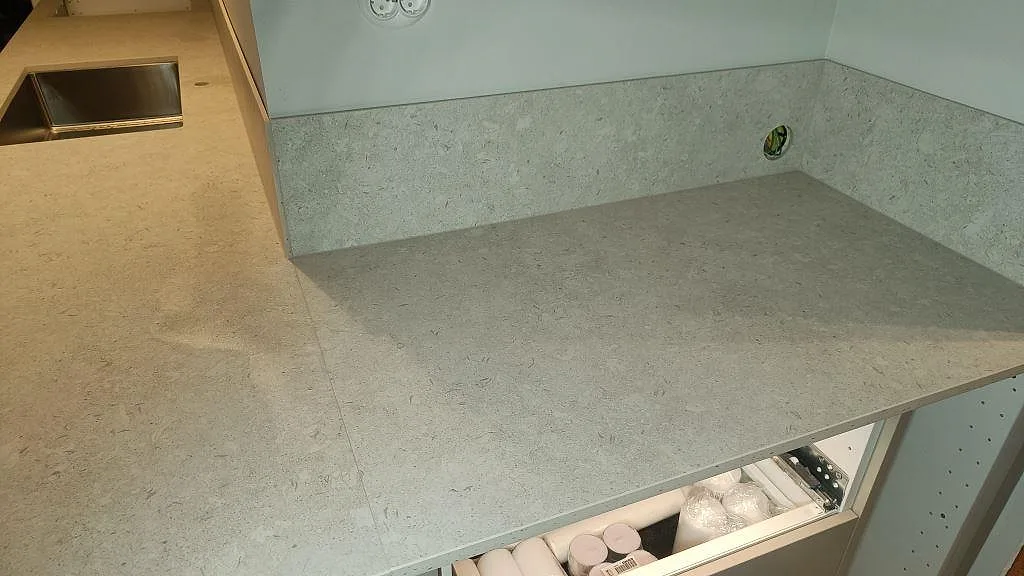 Köksbänkskiva i matt Dekton VK01 Nebbia med halvö, låg stänkkant och diskho vid L-delen i Asarum.
