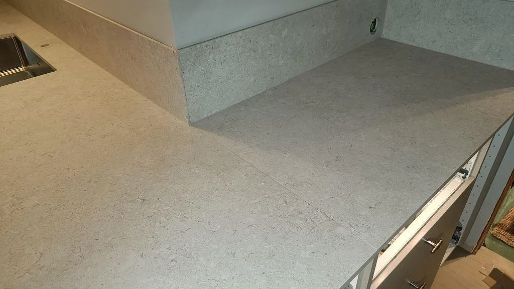 Detalj av matt Dekton VK01 Nebbia på halvön med uppvikt stänkskydd och installerad bänkskiva i Asarum.