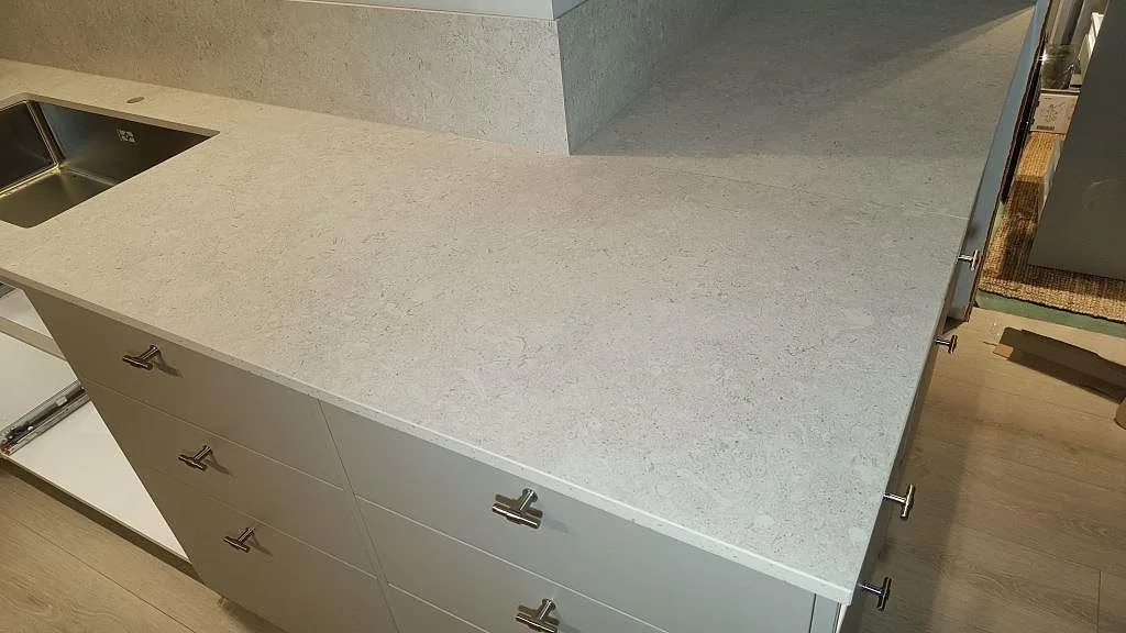 Matt köksbänkskiva i Dekton VK01 Nebbia över grå köksstommar med halvö och synlig stenstruktur i Asarum.