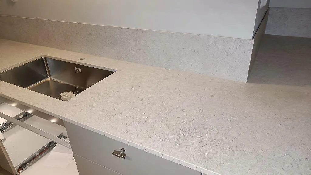 Närbild på matt Dekton VK01 Nebbia som köksbänkskiva med underlimmad rostfri dubbelho och uppvikt stänkskydd i Asarum.