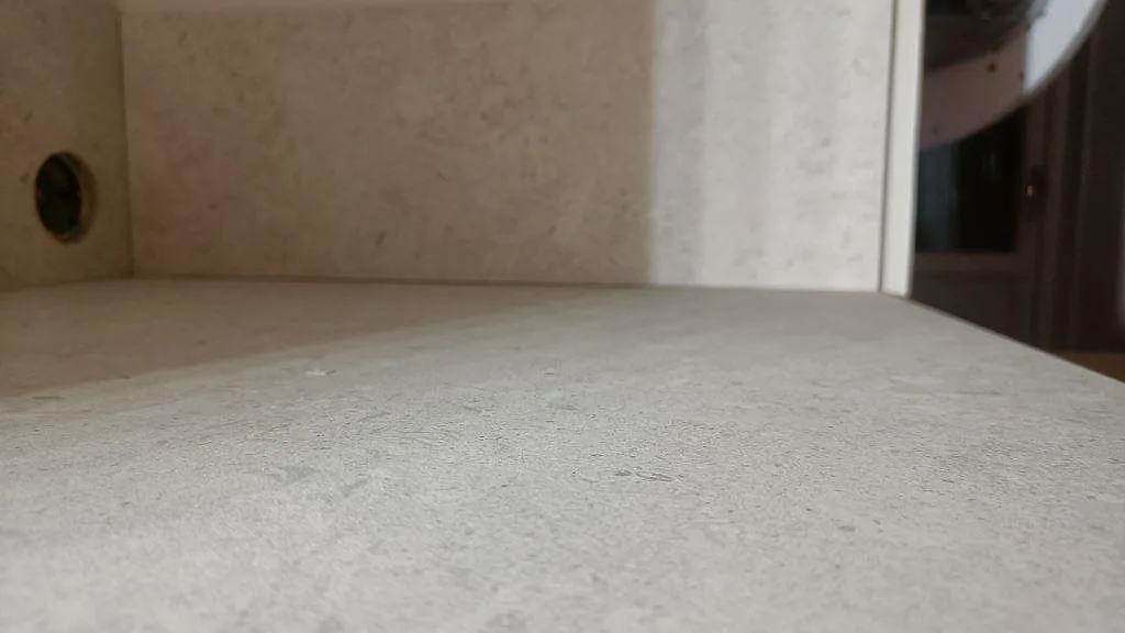 Låg närbild på ytan i matt Dekton VK01 Nebbia med uppvikt stänkskydd bakom köksbänkskivan i Asarum.