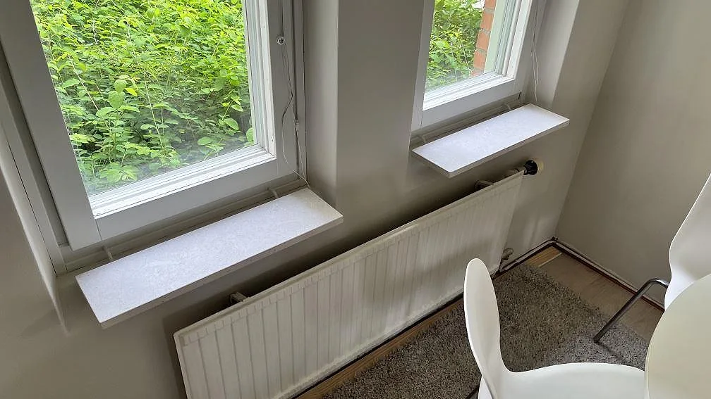 Fönsterbänkar i matt Dekton VK01 Nebbia, ljus keramik, monterade framför två fönster i Bromma.