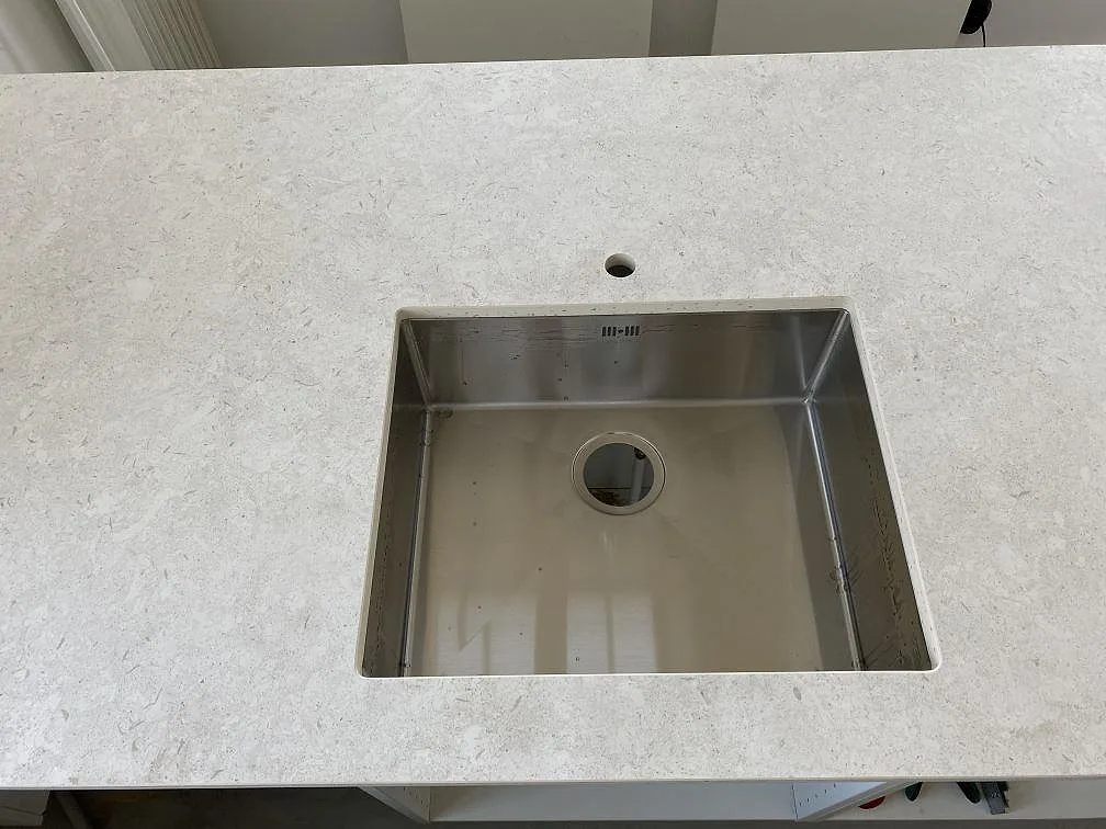 Detalj av diskho i en matt Dekton VK01 Nebbia bänkskiva med ljus stenstruktur i Eslöv.