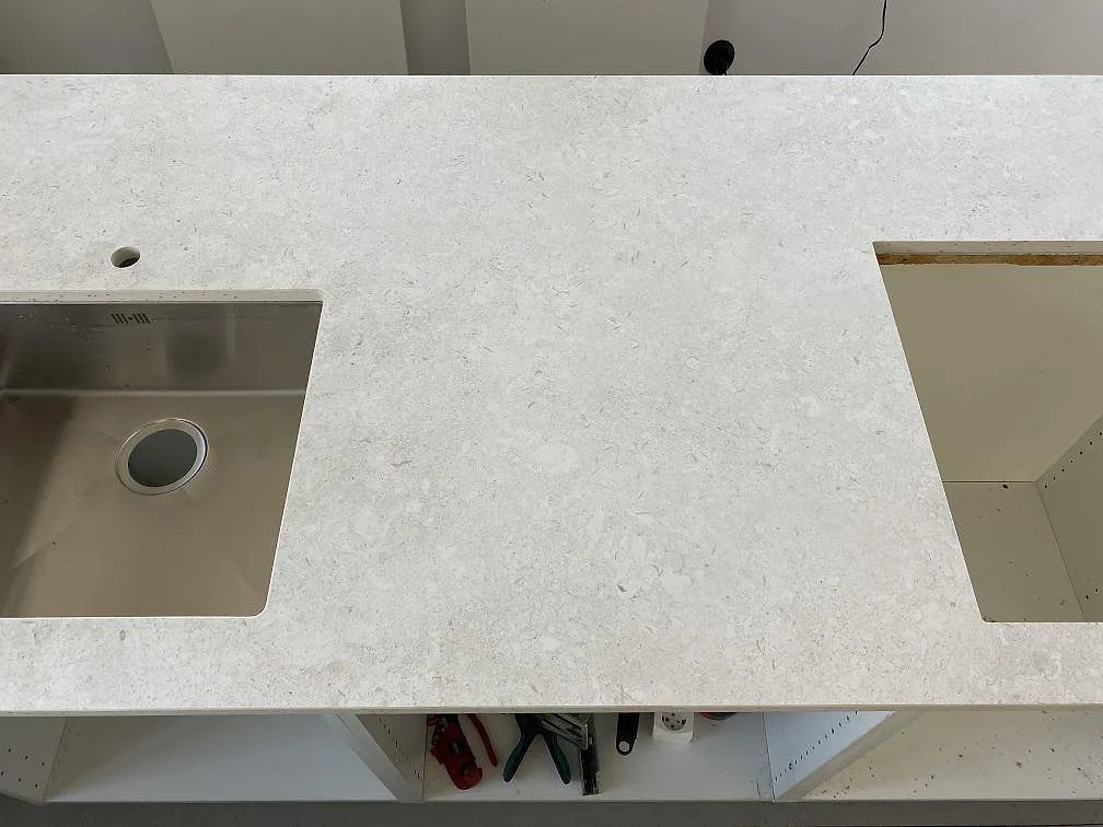 Topvy över matt Dekton VK01 Nebbia bänkskiva med rostfri diskho, blandarhål och större utskärning i Eslöv.