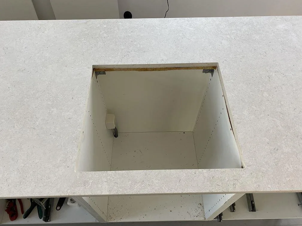 Detalj av större ursåg i matt Dekton VK01 Nebbia bänkskiva under köksmontering i Eslöv.
