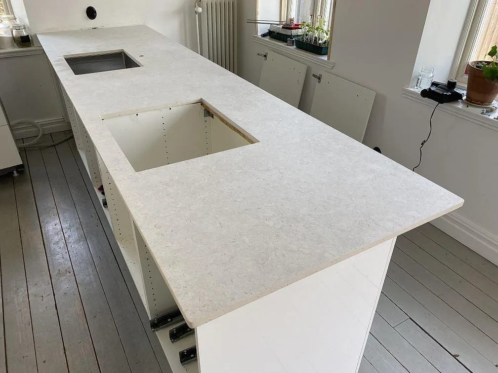 Lång köksbänkskiva i 20 mm matt Dekton VK01 Nebbia med diskho och stort ursåg i köket i Eslöv.