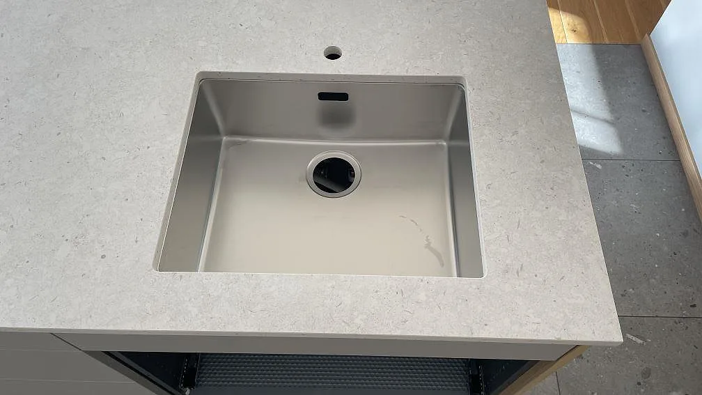 Närbild på underlimmad rostfri diskho i matt Dekton VK01 Nebbia med ljus stenstruktur i köket i Helsingborg.