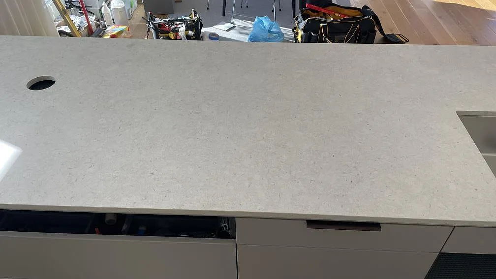Ytdetalj av matt 20 mm Dekton VK01 Nebbia med kranhål, diskhodel och ljus stenstruktur i Helsingborg.
