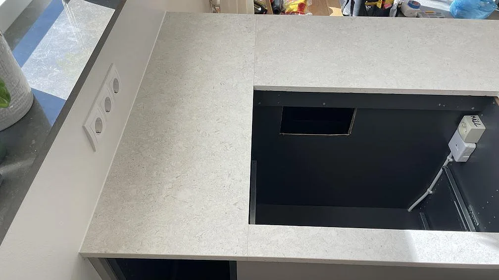 Köksbänkskiva i matt Dekton VK01 Nebbia vid fönster och vägguttag med utskärning för häll i Helsingborg.