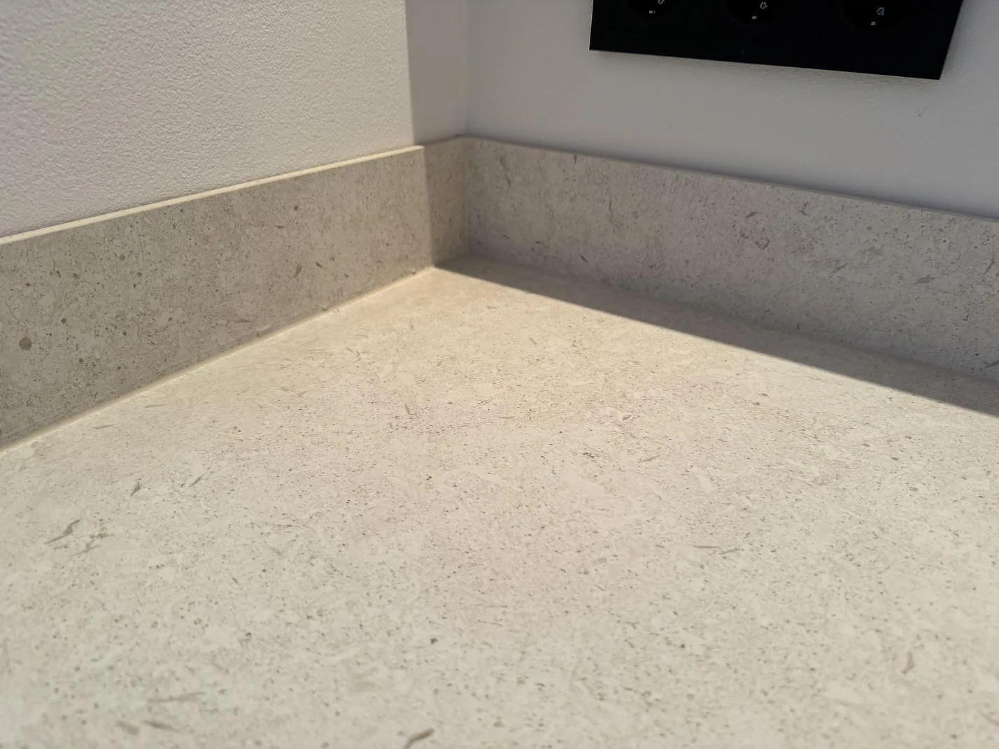 Närbild på matt Dekton VK01 Nebbia med beige betonglik struktur och låg stänkkant i ett kök i Höllviken.