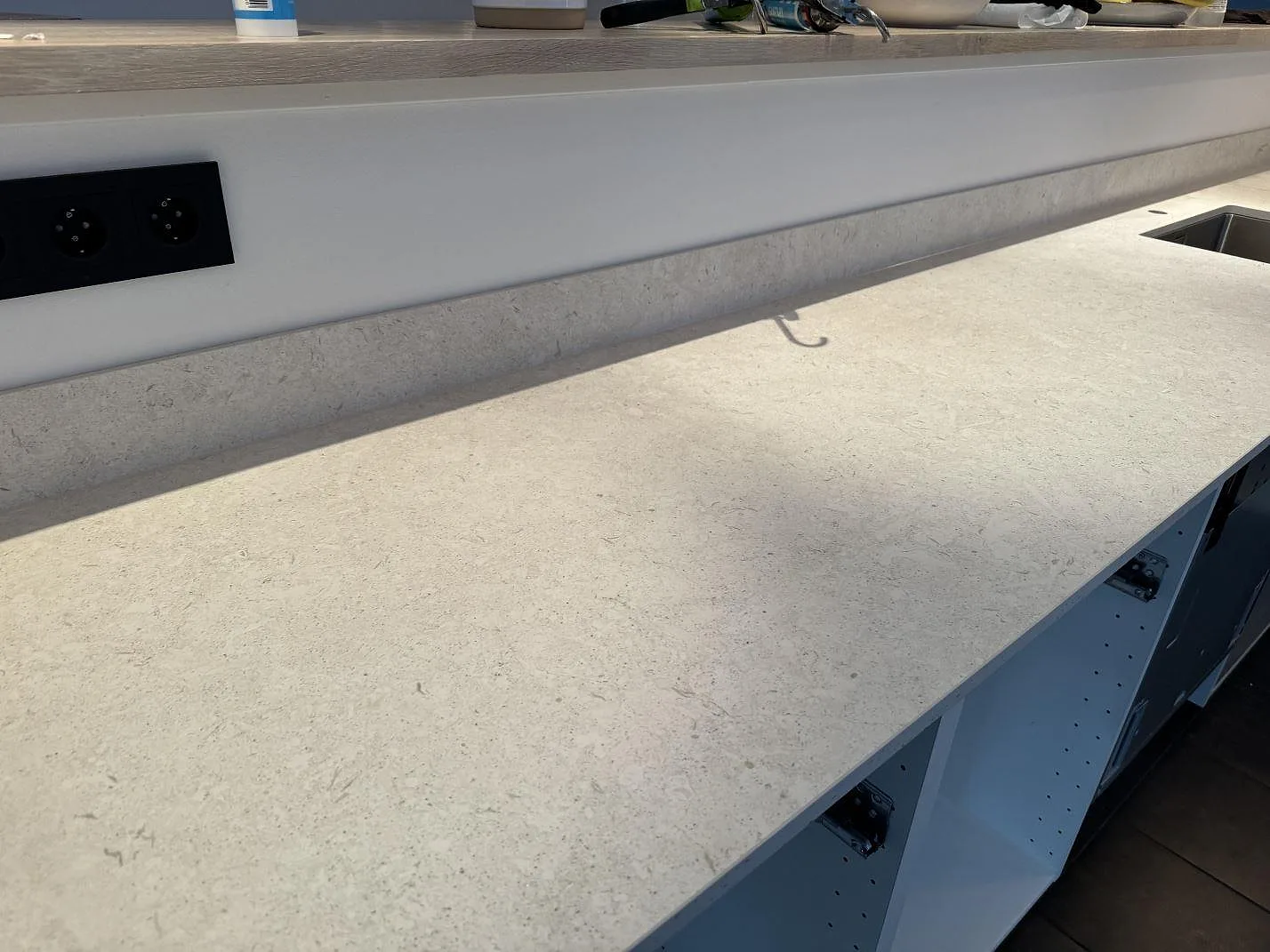 Lång köksbänkskiva i matt Dekton VK01 Nebbia med 8 mm stänkkant och rostfri diskho i ett kök i Höllviken.