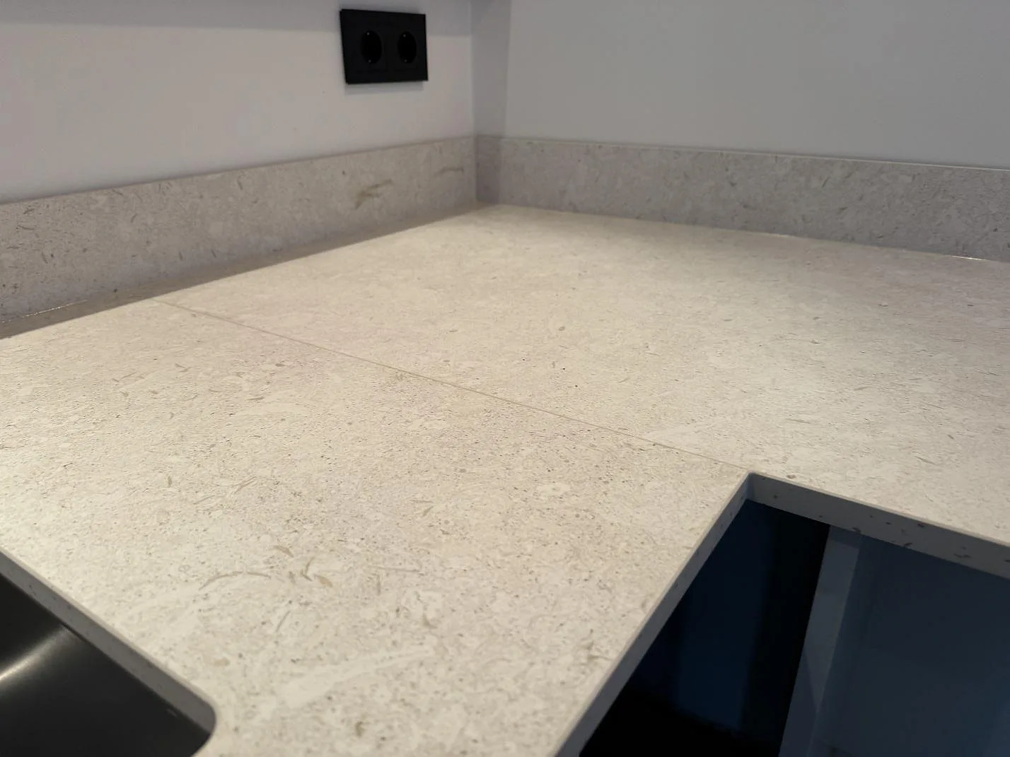 Hörndel av köksbänkskiva i matt Dekton VK01 Nebbia med diskho och 8 mm stänkkant under montering i Höllviken.