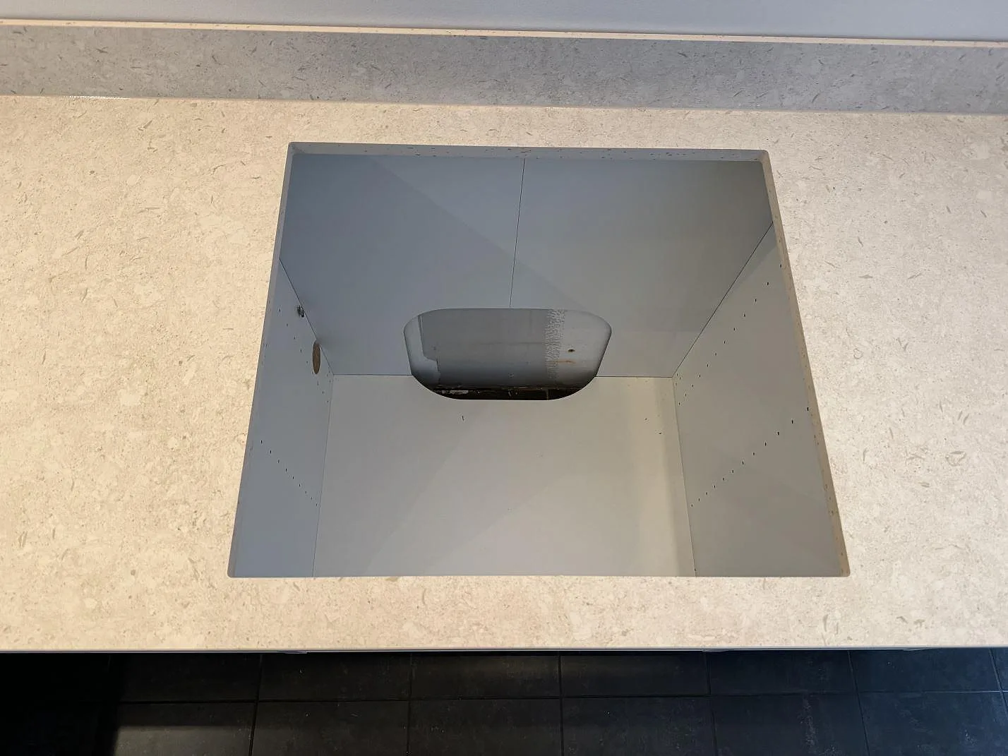 Hällöppning i matt Dekton VK01 Nebbia köksbänkskiva med stänkkant och vita skåpstommar i Höllviken.