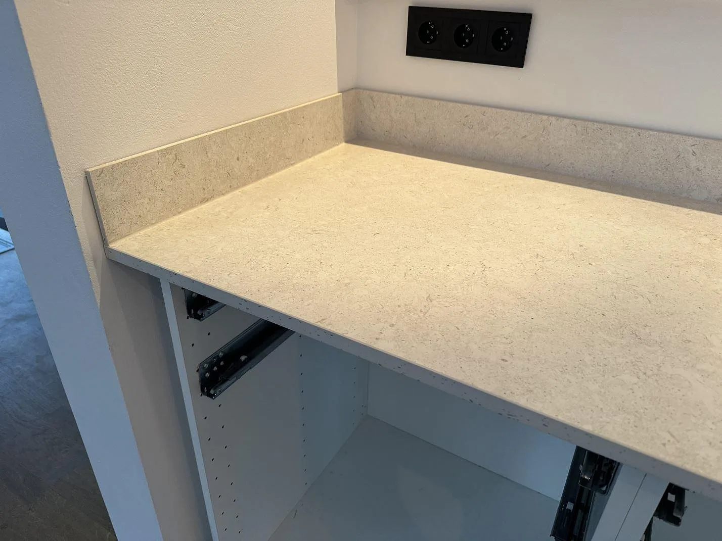Dekton VK01 Nebbia köksbänkskiva i 20 mm matt keramik med uppvikt stänkkant över vita skåpstommar i Höllviken.