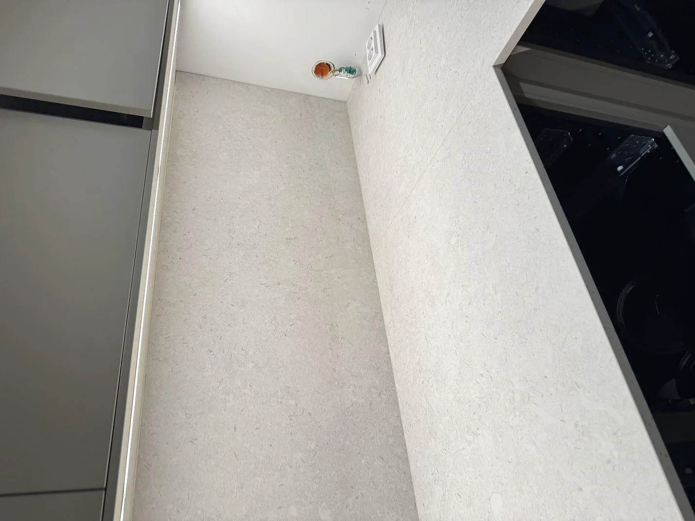 Stänkskydd och bänkskiva i matt Dekton VK01 Nebbia keramik med eluttag under montering i Höllviken.