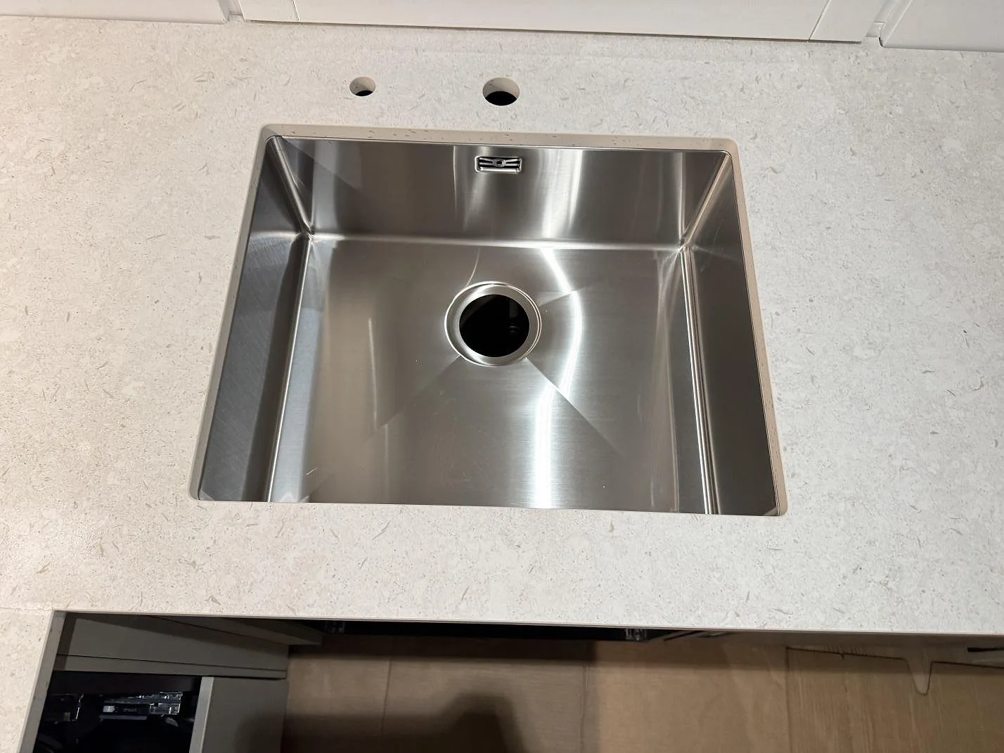 Detalj av matt Dekton VK01 Nebbia keramik runt en rostfri diskho i köket i Höllviken.