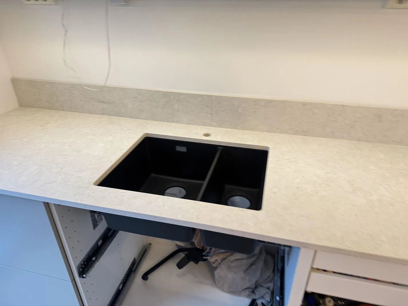 Närbild på köksbänkskiva i matt Dekton VK01 Nebbia med svart diskho och uppvikt stänkskydd i Lindome.